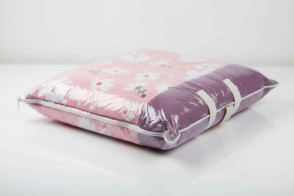 Pink floral pillow with clear plastic wrap on a white background